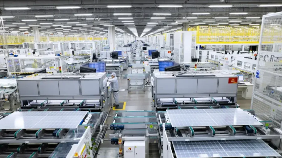 A spacious factory interior with automated machinery, conveyor lines, and a worker in protective clothing.